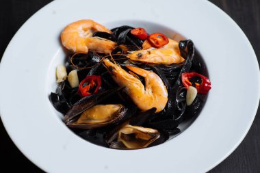 Taze karides ve üzerinde siyah makarna midye