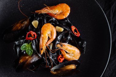 Taze karides ve üzerinde siyah makarna midye