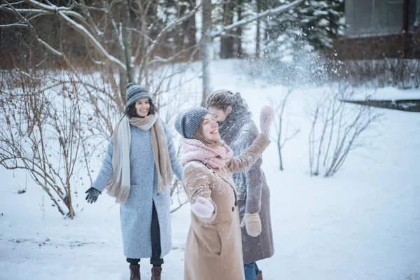 Três jovens mulheres brincando na neve — Fotografia de Stock