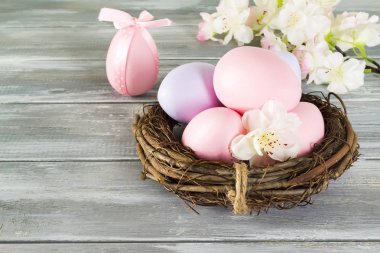 Bir yuva ile bahar çiçekleri ahşap gri arka plan üzerinde renkli el yapımı yumurta mükemmel. Mutlu Paskalya