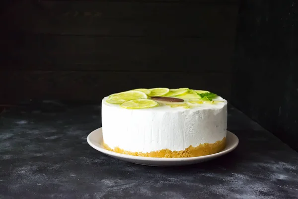 Gâteau appétissant avec tranches de citron vert sur un fond sombre — Photo