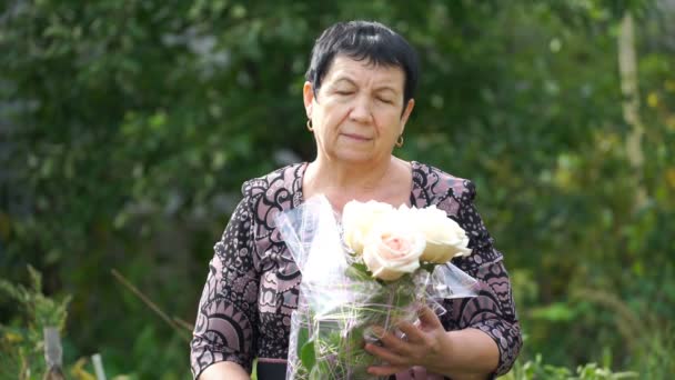 Materiał filmowy starszą kobietę z bukietem róż na zewnątrz. 4k — Wideo stockowe