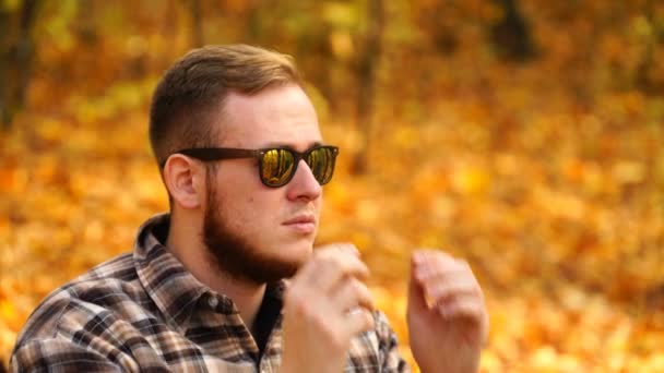 Imágenes de un hombre poniéndose gafas de sol al aire libre en otoño. 4K — Vídeo de stock