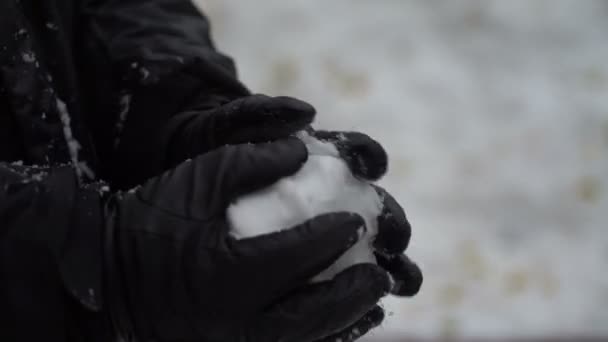 Homem de filmagem esculpe mãos uma bola de neve ao ar livre. 4K — Vídeo de Stock