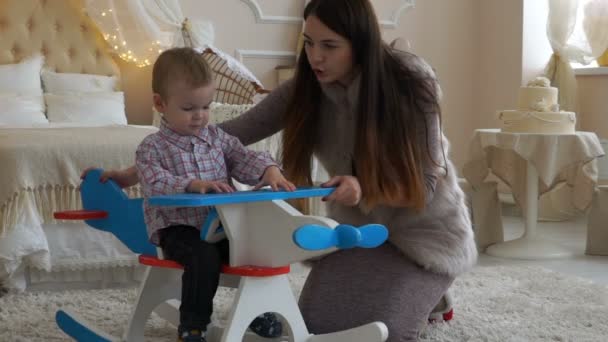 Мама катит своему сыну игрушечный самолет — стоковое видео