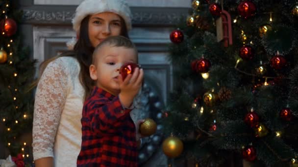 Мама со своим сыном снимает рождественскую елку. 4K — стоковое видео