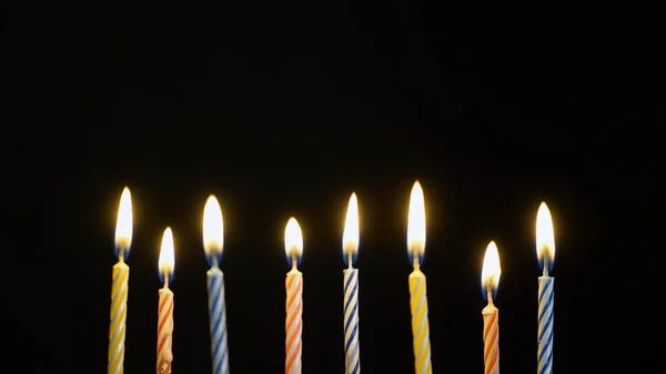 Colorful burning candles set on black background — Stock Photo, Image