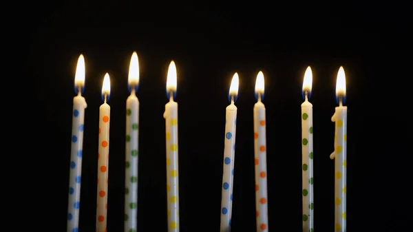Bunte brennende Kerzen auf schwarzem Hintergrund — Stockfoto