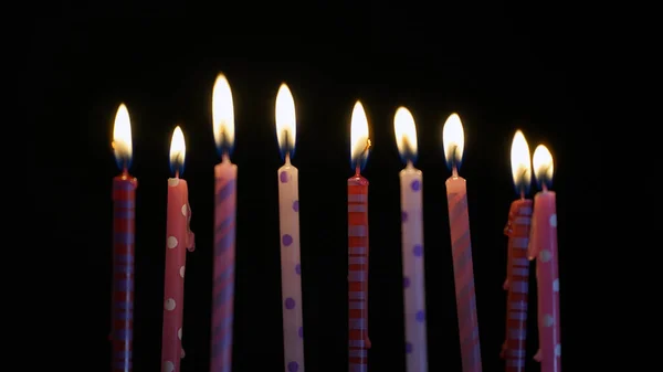 Velas ardientes de colores sobre fondo negro — Foto de Stock