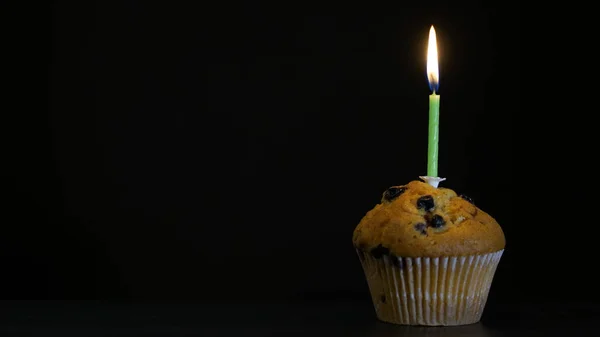 Muffin mit Kerze in Nahaufnahme auf schwarzem Hintergrund — Stockfoto