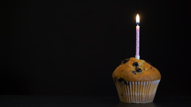 Muffin de filmación con una vela de cerca sobre fondo negro. Vídeo 4K — Vídeos de Stock