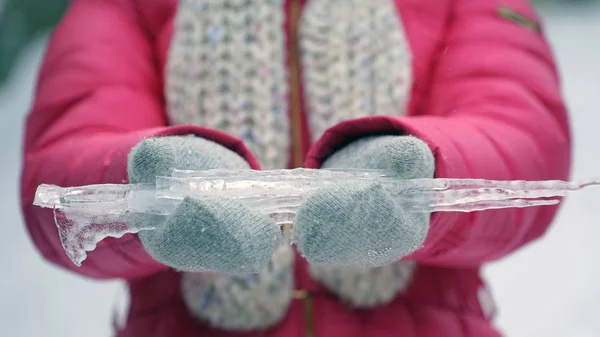 Mujer sosteniendo el carámbano en las manos al aire libre en invierno . — Foto de Stock