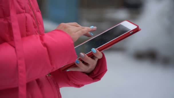 Beeldmateriaal vrouw met behulp van de tablet buitenshuis in de winter. 4k — Stockvideo