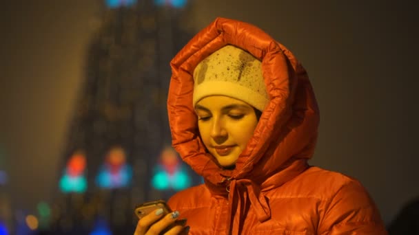 Filmación chica escribiendo un mensaje en su teléfono inteligente en el invierno en la calle . — Vídeo de stock