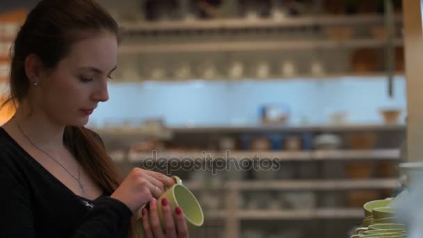 Frau kauft im Laden für eine Tasse Tee und eine Untertasse. — Stockvideo