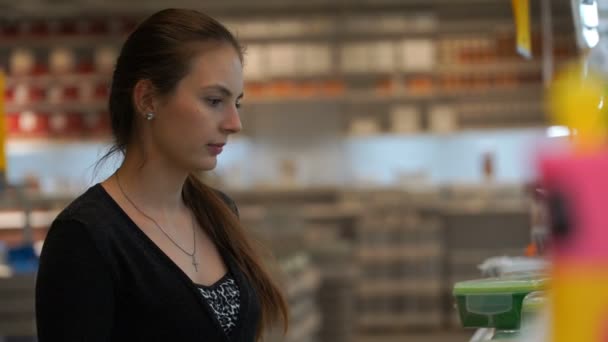 Mulher em uma loja comprando um recipiente de plástico para alimentos . — Vídeo de Stock