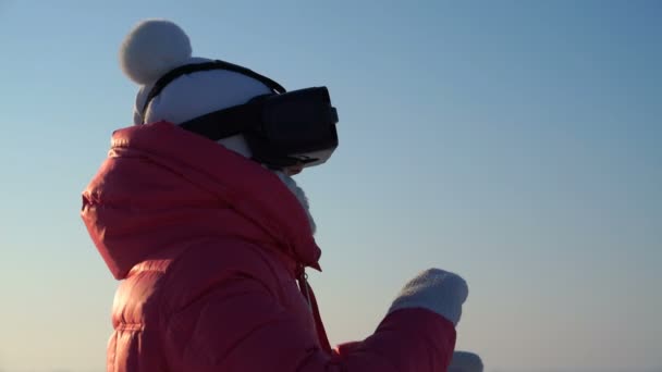 Menina olha nos óculos de realidade virtual ao ar livre no inverno. — Vídeo de Stock