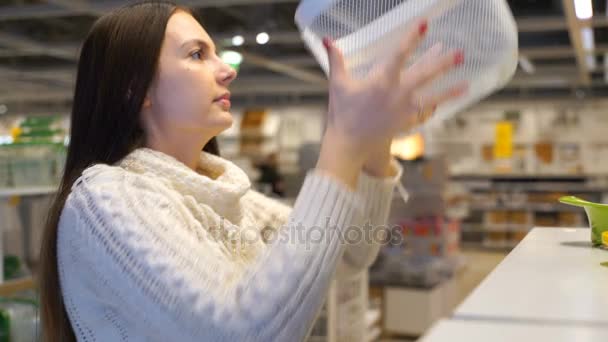 Vrouw koopt een kunststof mand in winkel. — Stockvideo