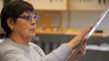 kadın bir kesme tahtası dükkanda seçer..