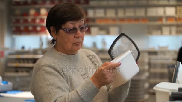 Frau in einem Geschäft beim Kauf eines Plastikbehälters für Lebensmittel. — Stockvideo