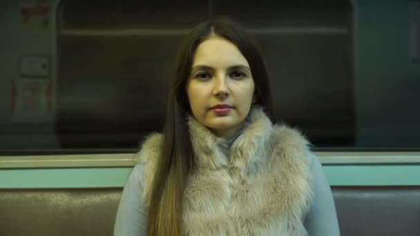 Молодая девушка едет в метро и смотрит в камеру . — стоковое видео