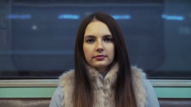 metro ve kameraya bakarak esmer kız rides.