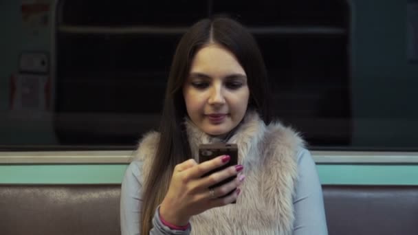 Chica morena monta en el metro y utilizar la aplicación en su teléfono inteligente — Vídeo de stock