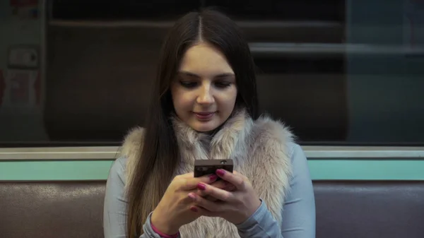 Брюнетка девушка едет в метро и использовать приложение на вашем смартфоне . — стоковое фото