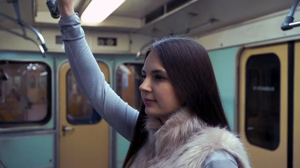 Молодая девушка едет в метро и держит перила . — стоковое фото