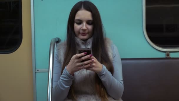 Brünettes Mädchen fährt in der U-Bahn und nutzt die App auf dem Smartphone. — Stockvideo