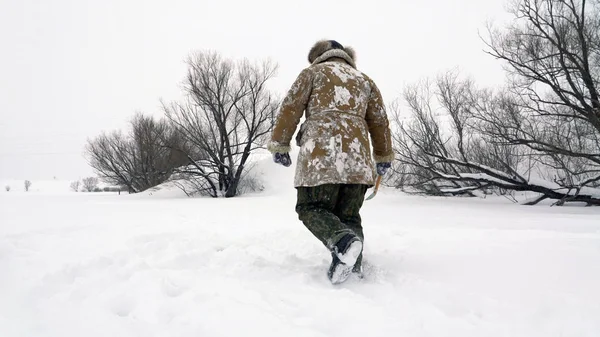 Een visser loopt op een besneeuwde meer op zoek naar een goede visserij plaats. — Stockfoto