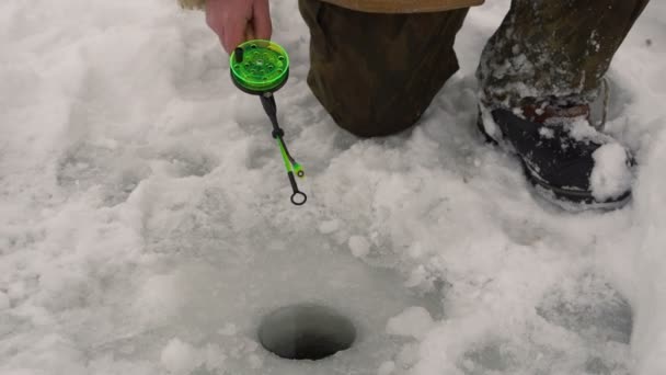 Pescador pega um peixe na pesca no gelo . — Vídeo de Stock
