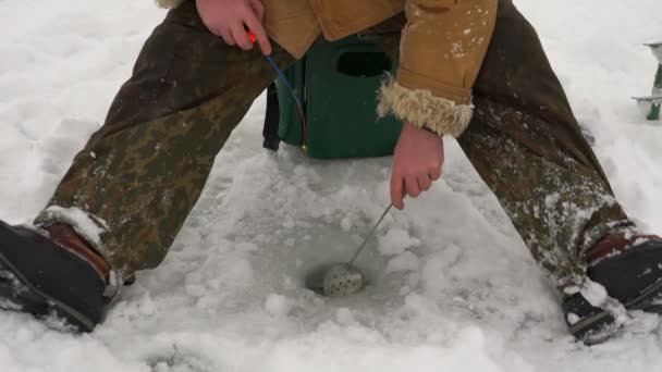 Рыбак ловит рыбу на ледяной рыбалке . — стоковое видео