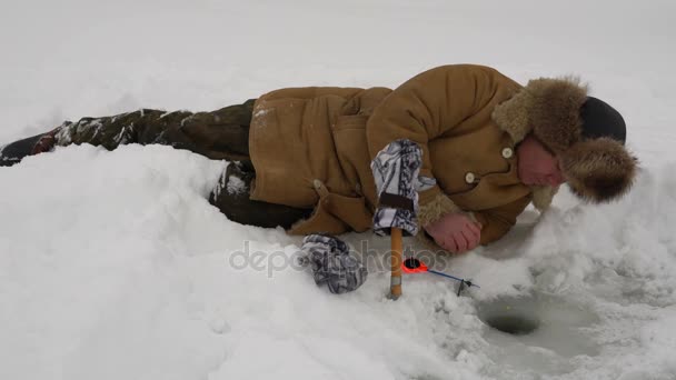 Fiskare fångar en fisk på isfiske. — Stockvideo