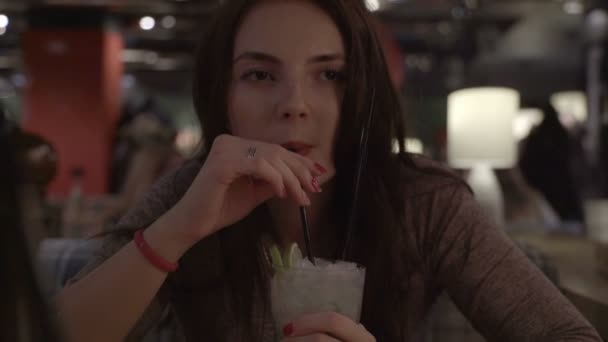 Woman sitting in a cafe and drinking mojitos. — Stock Video