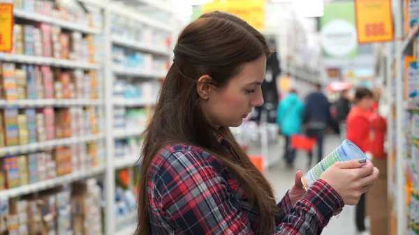 Young mom buys baby food in supermarket.