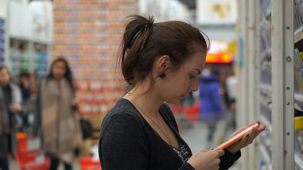 Mujer compra chocolate en un supermercado . — Foto de Stock