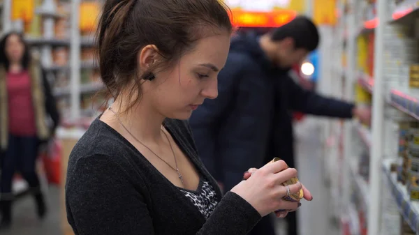Mujer compra comida enlatada en el supermercado — Foto de Stock