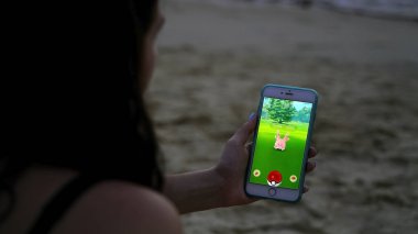 Phuket, Tayland - 28 Şubat 2017: kadın oyun pokemon git onun iphone 6s artı. Pokemon artar gerçeklik unsurları ile multiplayer oyun gidin. Corsola yakalandı.