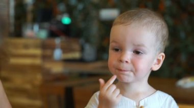 Küçük çocuk bir kafede yiyor.