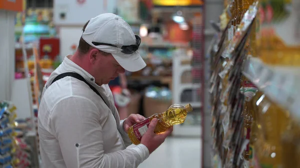 Férfi vásárol napraforgóolajat egy szupermarketben. — Stock Fotó