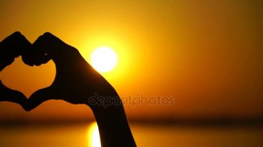 Kadın kalp yapar ve eller gün batımını yönlendirir
