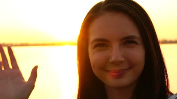 Молодая девушка делает селфи на фоне заката — стоковое видео