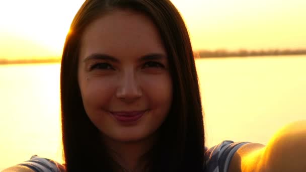 Νεαρό κορίτσι κάνει selfie σε φόντο ηλιοβασίλεμα — Αρχείο Βίντεο