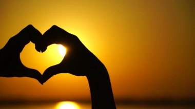 Kadın kalp yapar ve eller gün batımını yönlendirir