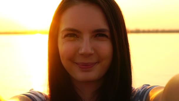 Chica joven haciendo selfie en el fondo de la puesta del sol — Vídeo de stock