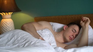 Adam yatakta uyuyor.
