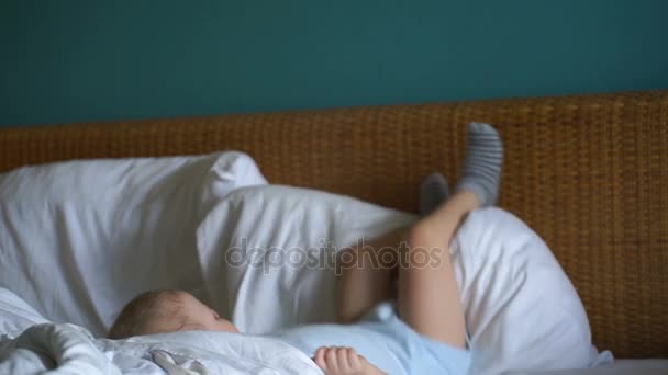 Μικρό αγόρι παίζει με τα πόδια του στο κρεβάτι. — Αρχείο Βίντεο