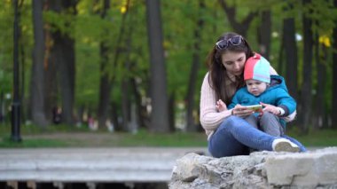 Anne ve oğlu parkta bir smartphone cep telefonu ile çizgi film izlerken.