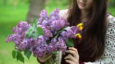 Bir buket leylak çiçeği içinde tutan kadın.